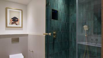 Un baño con inodoro, ducha con puerta de cristal y un cuadro en la pared.