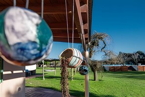 A covered outdoor area with hanging globes, a wooden structure, and a grassy field. - Oceana Suites Espacio Ganesha (Baradero)