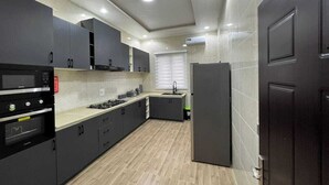 Une cuisine moderne avec des meubles de couleur sombre, un four encastré et un réfrigérateur.