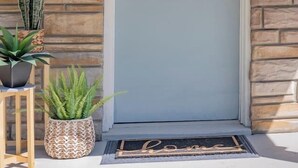 A front door with a number "1120" above it, a wreath, and two potted plants on either side. - Cozy 3BR Home | KING Bed | ONLY 8-Min to LU! (Lynchburg)