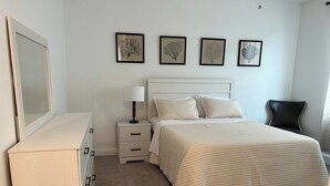 Une chambre à coucher comprenant un lit, des tables de chevet, une commode et des œuvres d’art encadrées accrochées au mur.