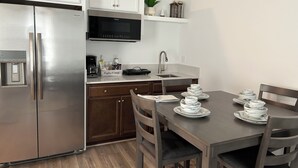 Une cuisine moderne dotée d’appareils électroménagers en acier inoxydable, d’un four à micro-ondes encastré et d’un coin repas avec une table dressée pour quatre personnes.