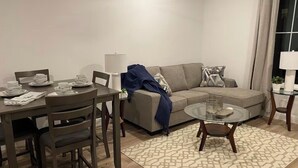 Un salon moderne avec une table à manger pour quatre personnes, un canapé et une table basse en verre.