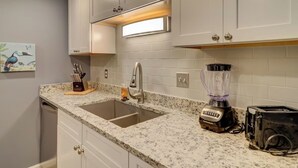 A kitchen with white cabinets, a granite countertop, a sink, a blender, and a toaster. - Spacious 3BR Hilton Head Getaway + Pool Access (Hilton Head Island)