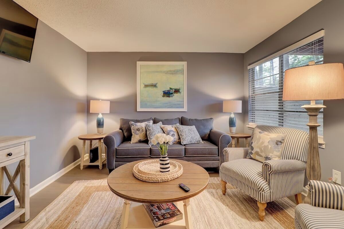 A living room with a sofa, armchairs, a coffee table, and a painting on the wall.