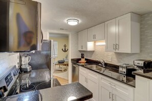 A modern kitchen with a black countertop, white cabinets, a blender, a toaster, and a sink. - Family 2BR Retreat Near Beach + Pool Hilton Head (Hilton Head Island)