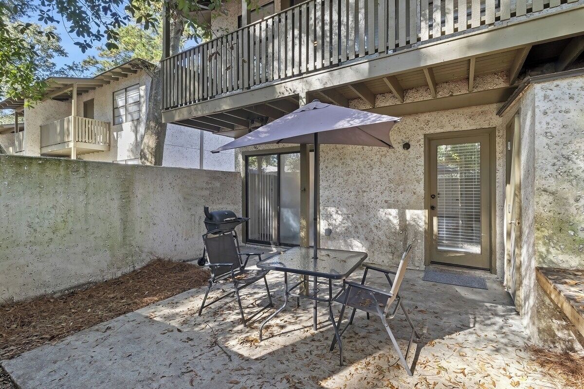 A patio with a table and chairs, a grill, and a covered seating area.