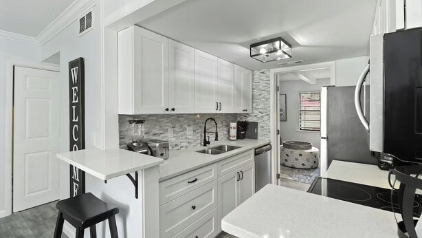 A modern kitchen with white cabinetry, a black countertop, and a built-in stove.