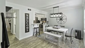 A modern kitchen with white cabinetry, a central island, and a hanging light fixture.
