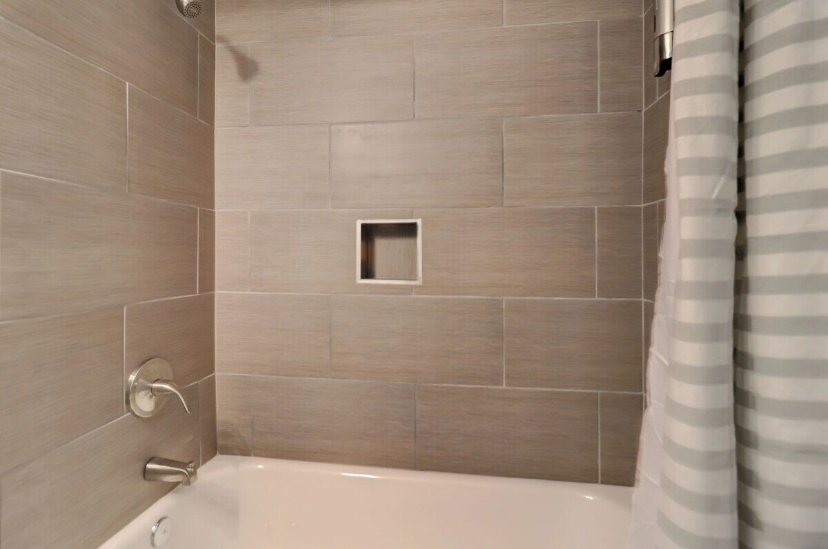 A modern bathroom with beige tiles, a shower area, and a bathtub.