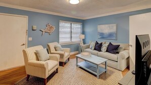 A living room with a beige sofa, two striped armchairs, a coffee table, and a TV. - Beach Getaway 2BR w/ Pool + Modern Comforts (Hilton Head Island)