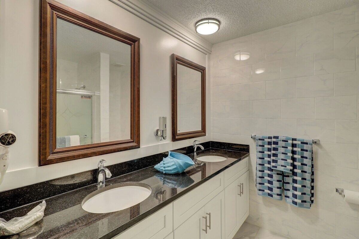 A bathroom with two sinks, large mirrors, and a towel rack.
