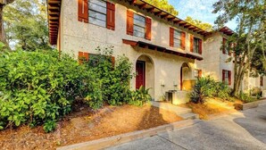 A two-story building with a stone facade, red shutters, and a central arched entrance. - Beach Getaway 2BR w/ Pool + Modern Comforts (Hilton Head Island)