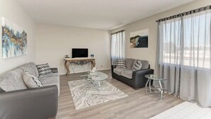 A modern living room with two sofas, a glass coffee table, and a TV on a wooden console. - Cozy Comfort/ 2-Bedroom Plainfield Getaway (Plainfield)
