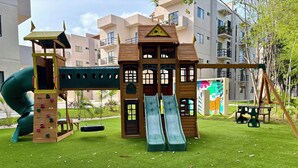 A playground with a slide, climbing wall, and swings.