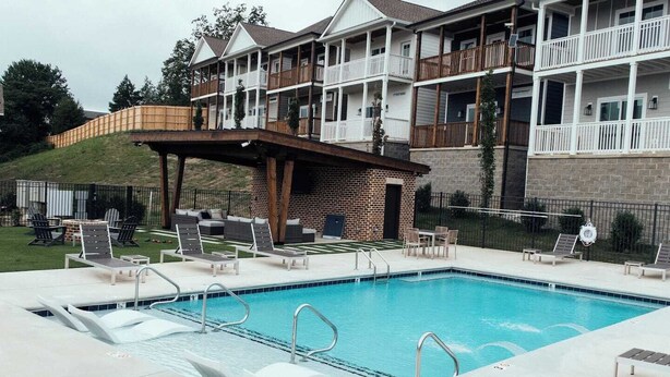 A pool area with lounge chairs, a covered seating area, and a building with balconies. - 121 Allison Way townhouse (Algood)