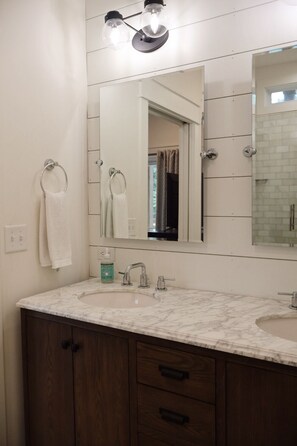 A bathroom with a large mirror, two towel rings, a sink, and a cabinet.