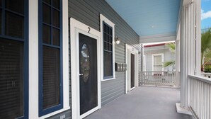 Un passage couvert, avec les portes numérotées 2 et 3, mène à un bâtiment dont le plafond est bleu et la rambarde, blanche.