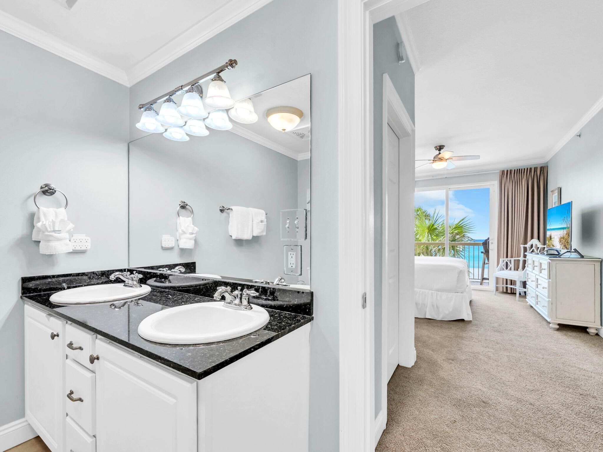 Un bagno moderno con doppio lavabo, un grande specchio e una ventola a soffitto.