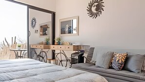A bedroom with a large bed, a sofa, a desk with plants, and a mirror. - Baja Desconocida Ranch Seaview (El Sargento)