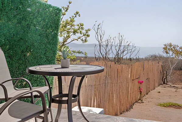 Une table ronde agrémentée d’un pot de fleurs, une chaise et une vue sur un paysage naturel avec une clôture en bois.