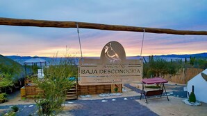 A sign for Rancho Baja Desconocida with a desert landscape in the background. - Baja Desconocida Ranch Seaview (El Sargento)