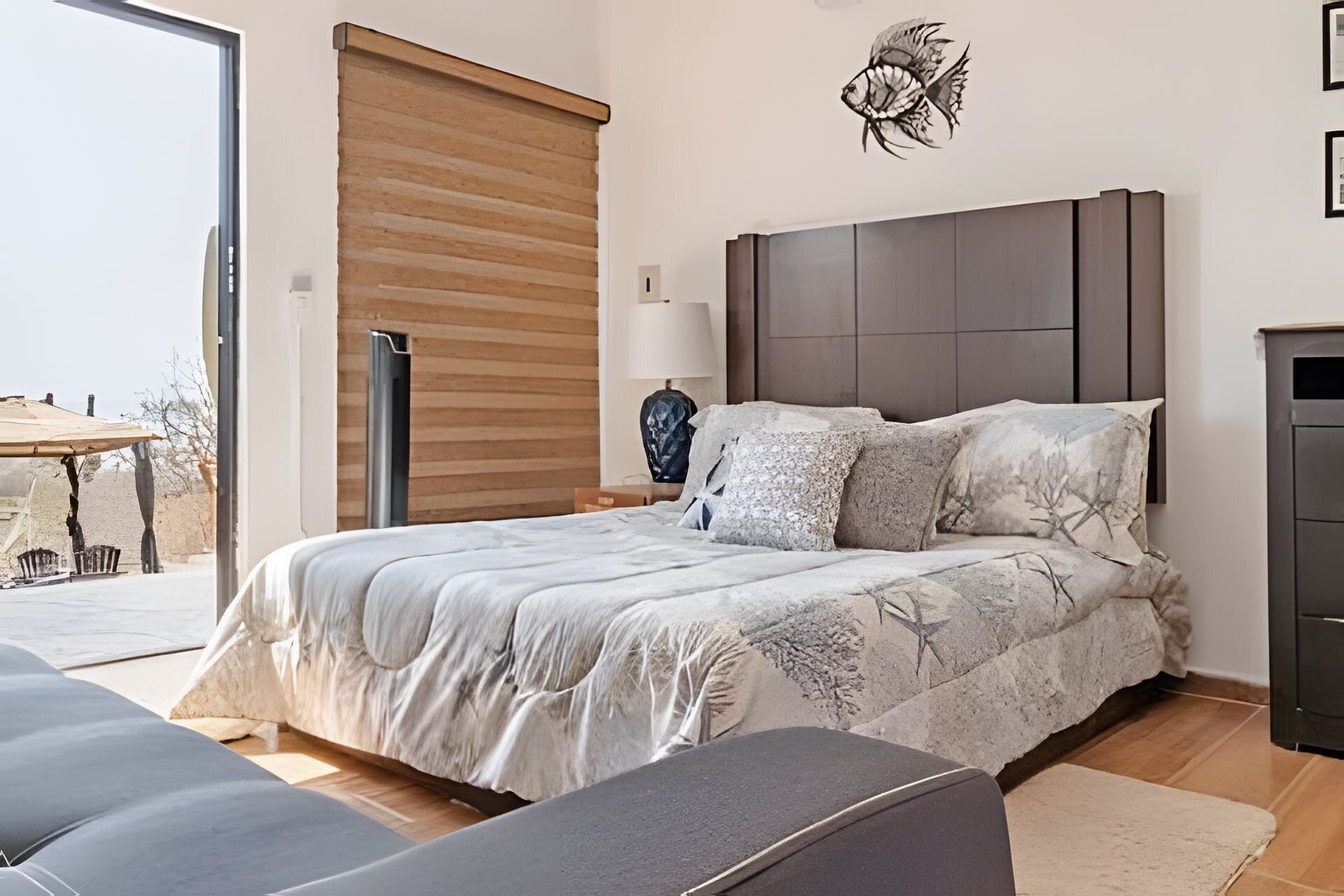 Un dormitorio con cama, mesita de noche, lámpara y una obra de arte en la pared.