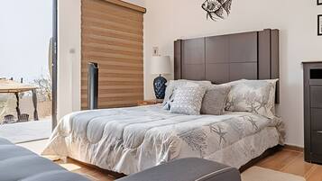 Un dormitorio con cama, mesita de noche, lámpara y una obra de arte en la pared.