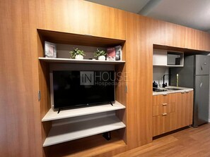 A kitchen with wooden cabinets, a built-in TV, and a microwave. - Jp redenção  (Porto Alegre)