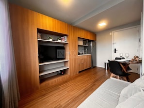 A modern kitchen with wooden cabinetry, a built-in TV, and a dining area with a table and chairs.