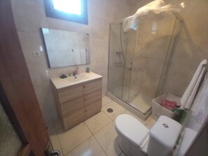 Une salle de bain équipée d’une douche, de toilettes et d’un meuble-lavabo avec un miroir et un porte-serviettes.