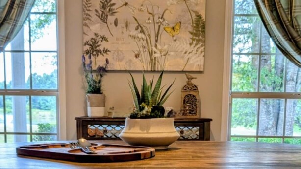 Een eettafel met twee stoelen, een bloempot en een decoratief object aan de muur.