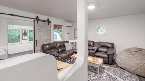 Un salon moderne avec un canapé en cuir marron, une table basse en bois et un grand pouf.