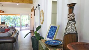 A living room with a sofa, a coffee table, a potted plant, and a decorative vase. - Amori Villa & Cabin (Rarotonga)