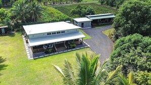 A two-story building with a flat roof, surrounded by lush greenery and a well-maintained lawn. - Amori Villa & Cabin (Rarotonga)