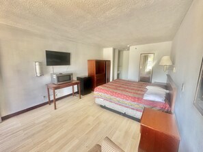 A bedroom with a bed, a TV, a desk, a wardrobe, and a lamp. - Albuquerque lnn   (Albuquerque)