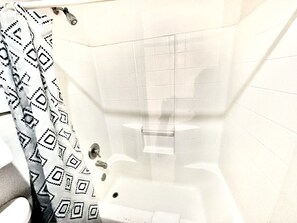 A bathroom with a patterned shower curtain, a white tiled wall, and a bathtub.