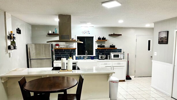 A modern kitchen with a central island, white cabinets, and a dining area with two chairs. - 3-bedroom house w/pond next to White Oak Lake (Chidester)