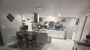 A kitchen with white cabinets, a dining table with chairs, a microwave, and a refrigerator. - 3-bedroom house w/pond next to White Oak Lake (Chidester)