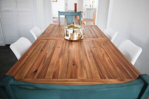 A wooden dining table with chairs, a teal cushion, and a metallic object on the table. - Historic 3BR Near Riverwalk | Corporate/Relocation • Wi-Fi • W/D • 30+ Nights (San Antonio)