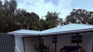 A swimming pool with a covered patio area, a table and chairs, and a sofa. - Gisella‘s Beach House II
Five minute drive to the beach (Vero Beach)