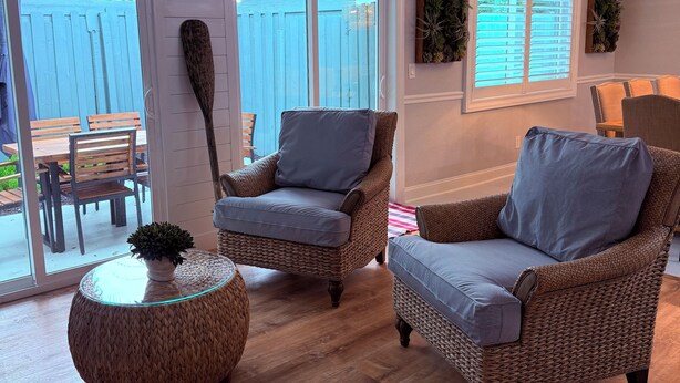 A cozy living room with wicker furniture, a glass coffee table, and a view of a blue fence outside. - Gisella‘s Beach House II
Five minute drive to the beach (Vero Beach)