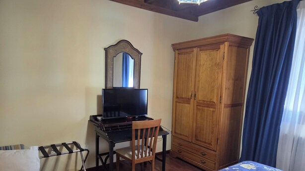 A bedroom with a bed, a desk with a TV, a wardrobe, and a chair. - Hotel Rural Las Farolas (El Espinar)