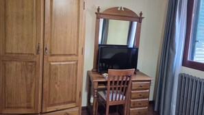 A wooden desk with a television, a chair, and a cabinet. - Hotel Rural Las Farolas (El Espinar)