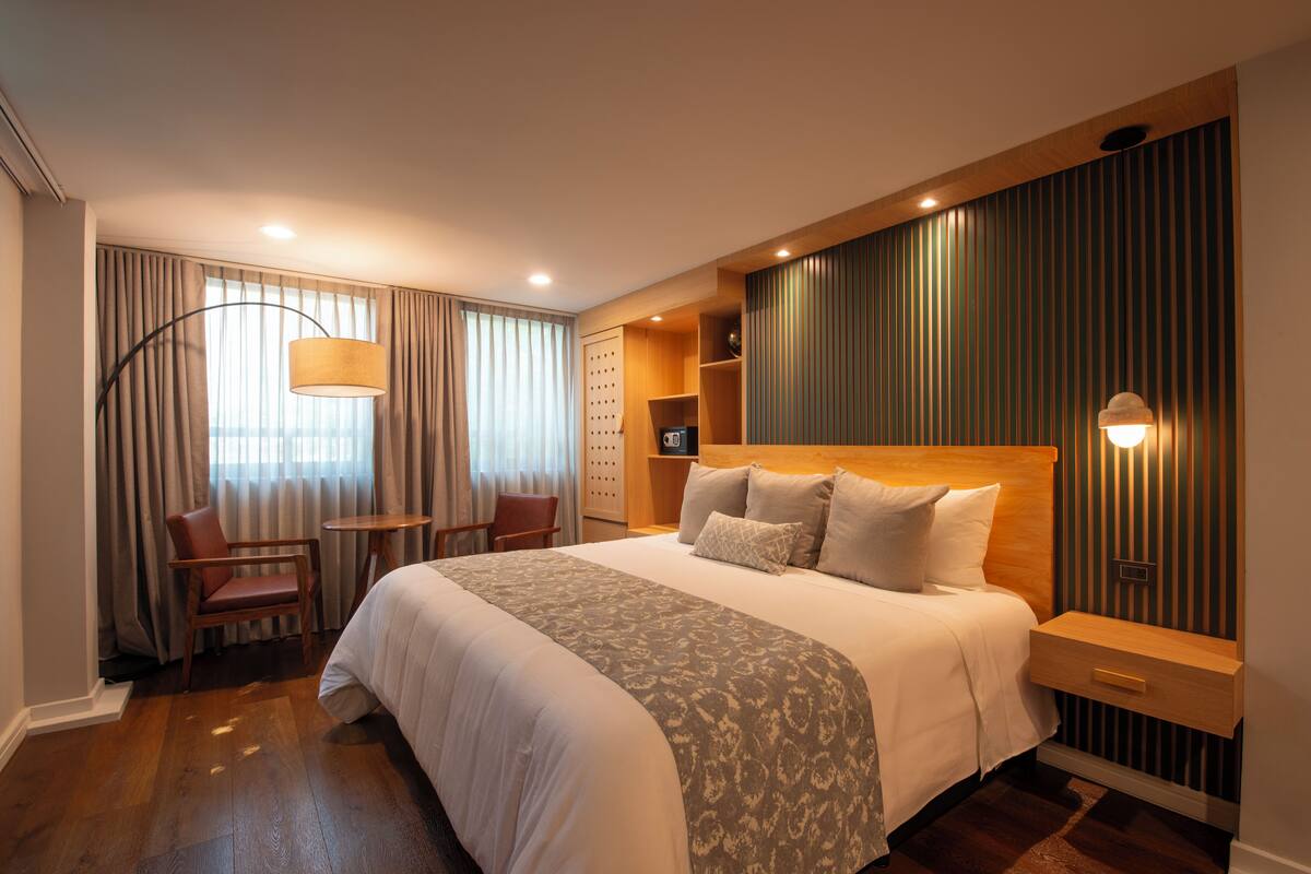 Una habitación de hotel moderna con una cama grande, un escritorio y una silla.