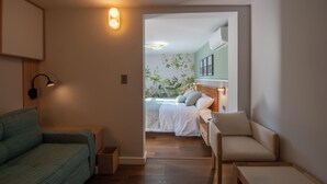 A bedroom with a bed, a nightstand, a chair, a sofa, and a small table. - Hotel Boutique Casa Flor de Café (Mexico City)