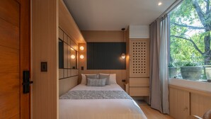 A modern bedroom with a wooden floor, a bed with white bedding, a large window with a view of trees, and a built-in wardrobe. - Hotel Boutique Casa Flor de Café (Mexico City)