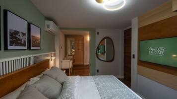 A hotel room with a bed, a TV, a mirror, and framed pictures on the wall.