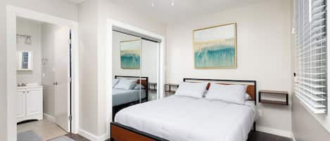 A bedroom with a bed, a ceiling fan, a painting, and a window with blinds.
