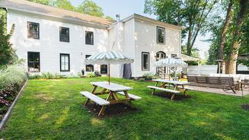 A white building with a well-maintained lawn and picnic tables with umbrellas.